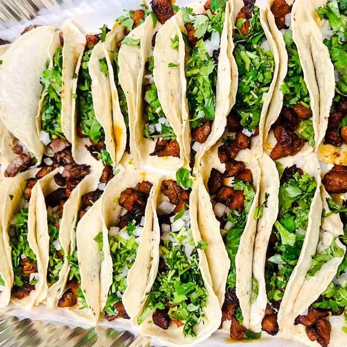 Tray of Mexican tacos with cilantro, onions, and seasoned meat