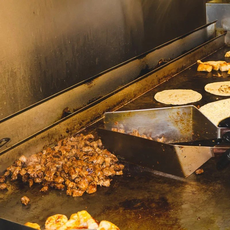 Mexican grill with sizzling meat and tortillas cooking